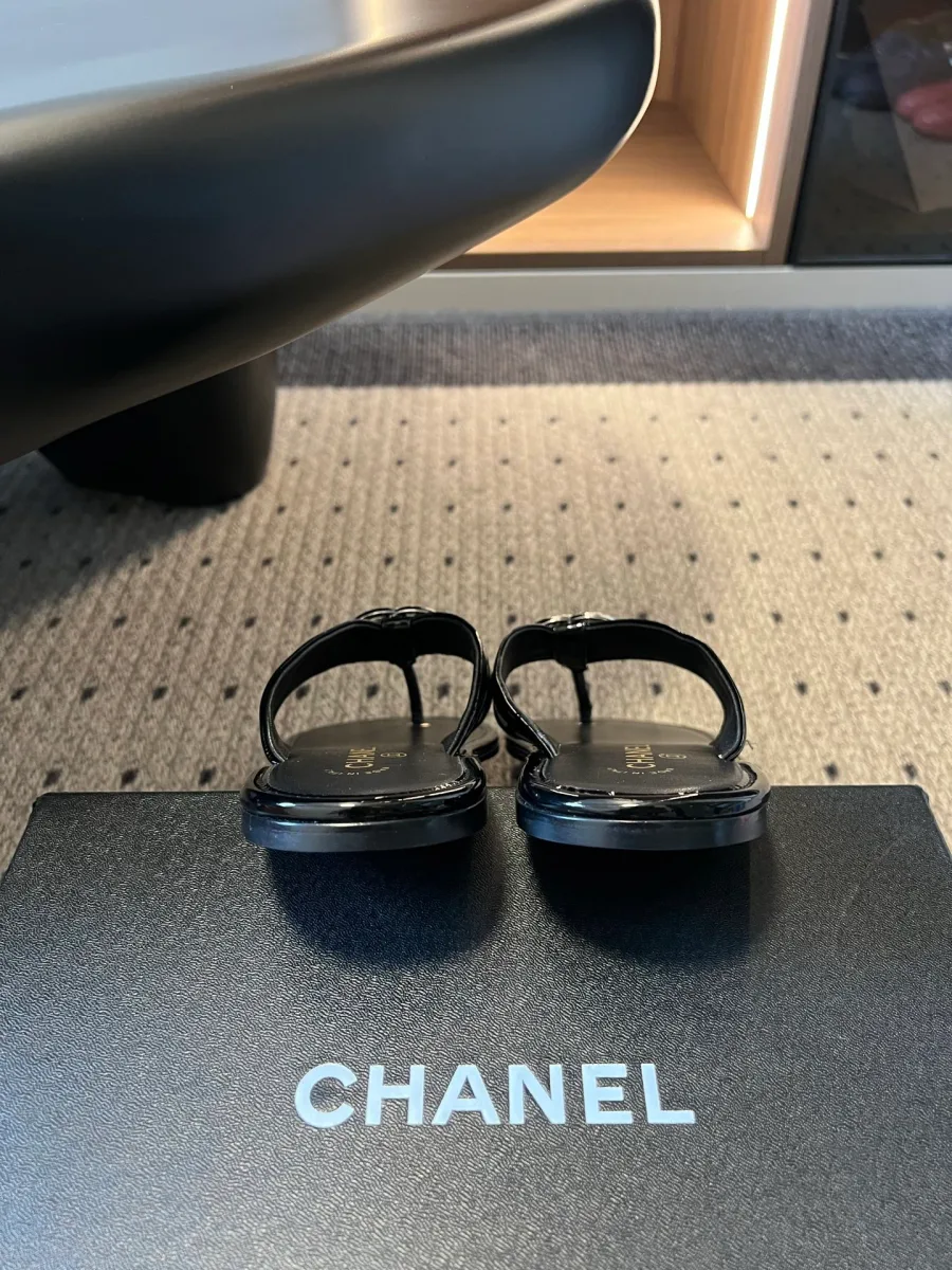 Вид со стороны пятки на чёрные шлёпанцы Chanel на фирменной коробке