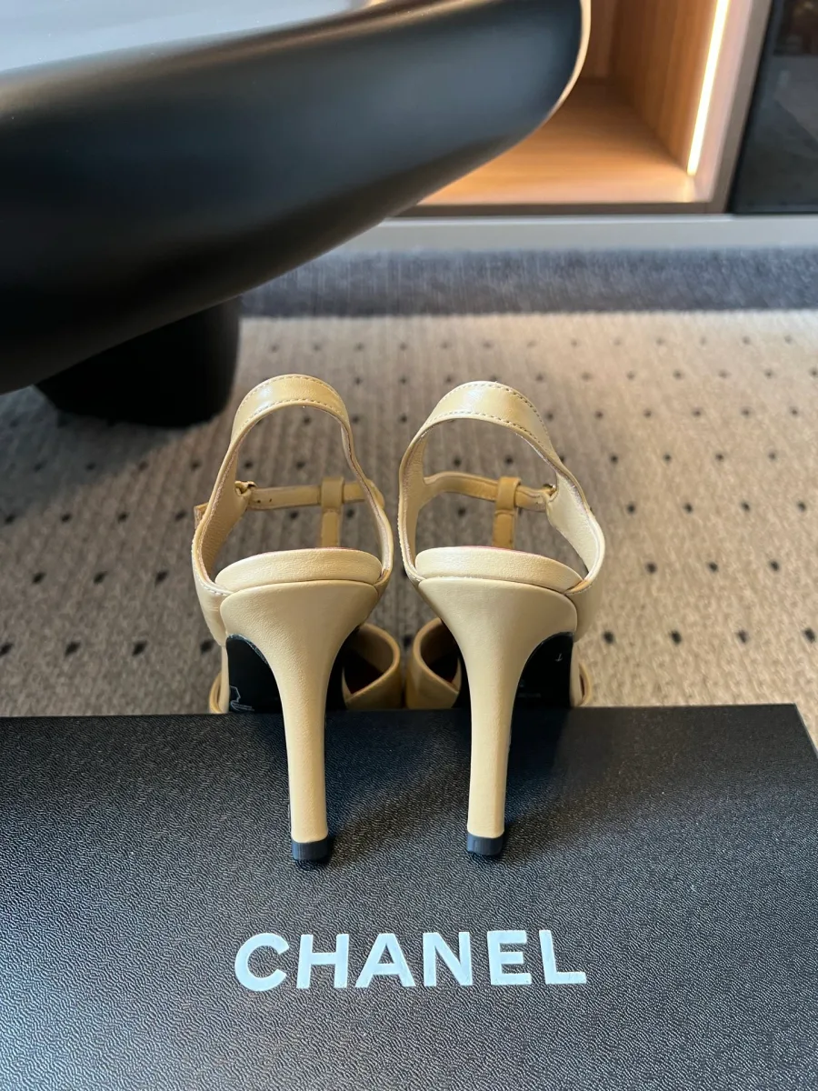 Вид сзади на каблуки-шпильки босоножек Chanel на фоне фирменной коробки