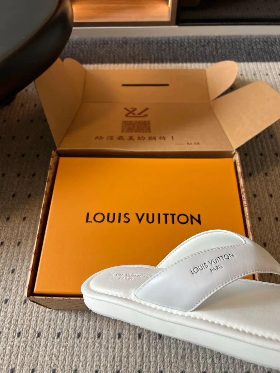 Крупный план широкого ремешка белого шлепанца с тиснёным логотипом Louis Vuitton