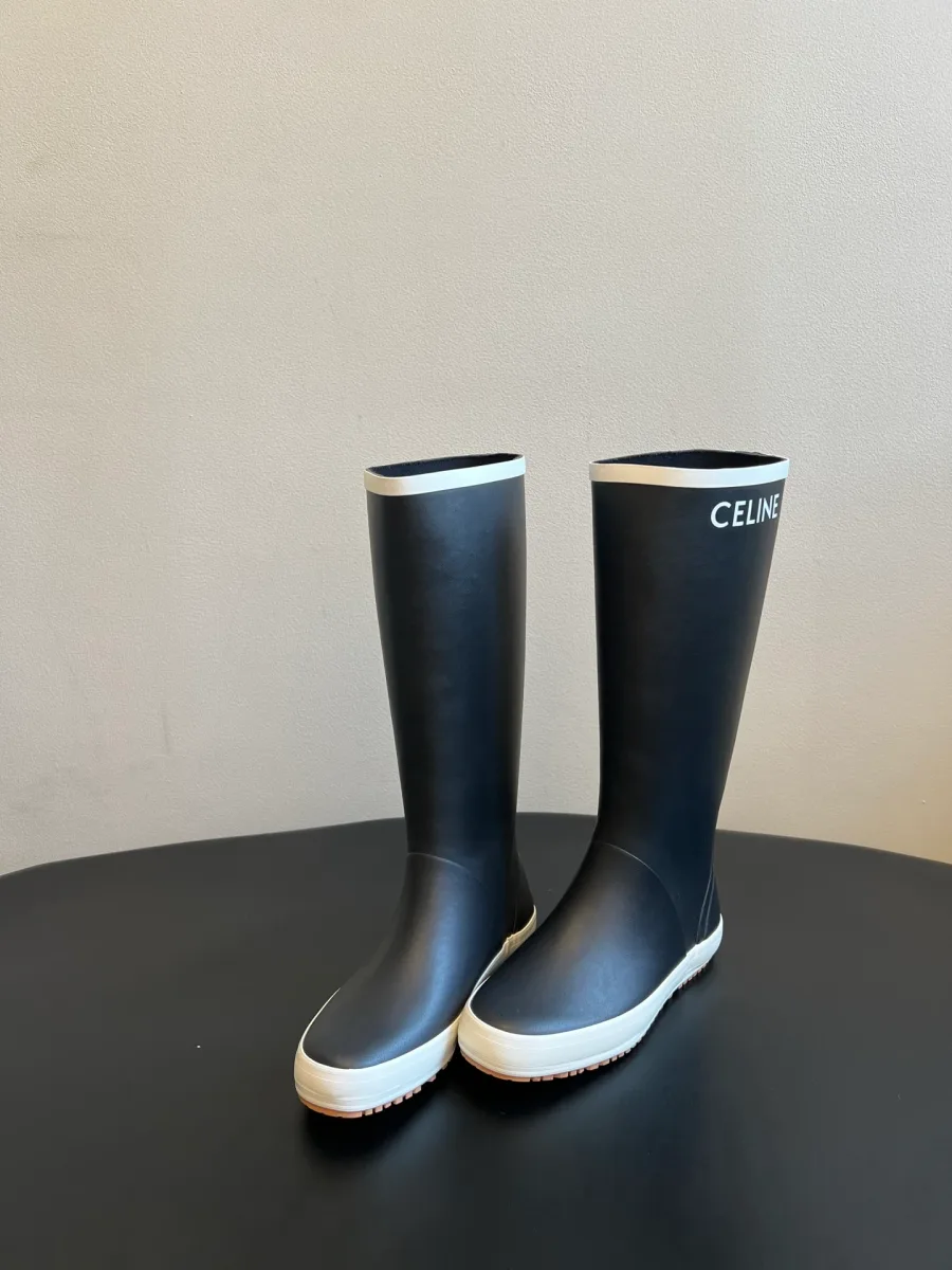 Пара чёрных сапог с белым кантом и надписью CELINE, ракурс три четверти
