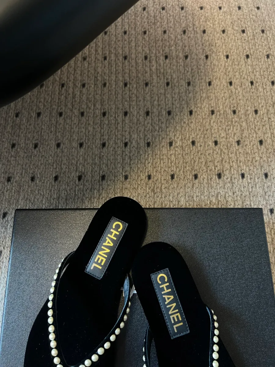 Крупный план бархатных стелек пары шлёпанцев с фирменными нашивками Chanel