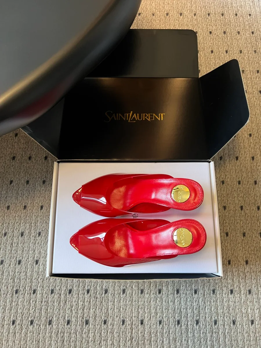 Пара красных лаковых мюлей Saint Laurent в открытой коробке, вид сверху