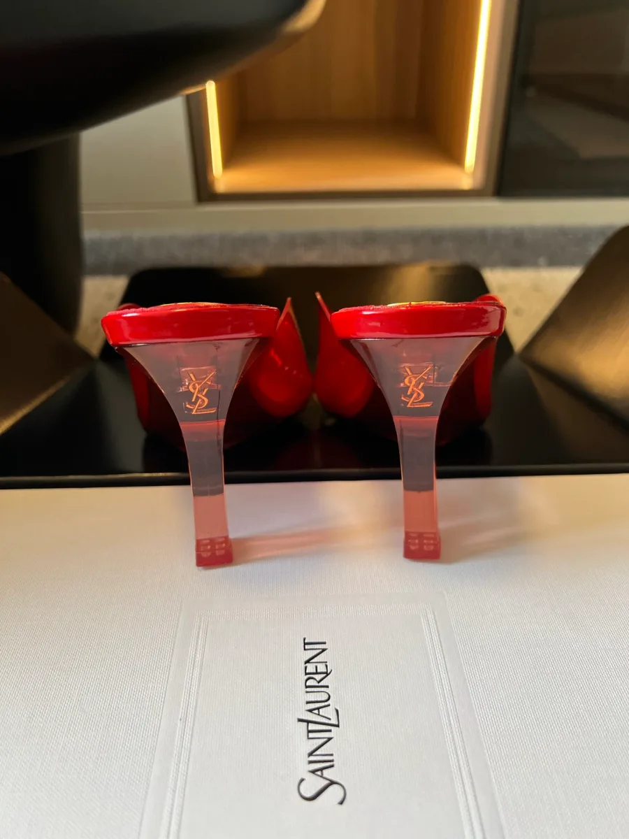 Вид сзади на прозрачные фигурные каблуки красных мюлей с логотипом YSL