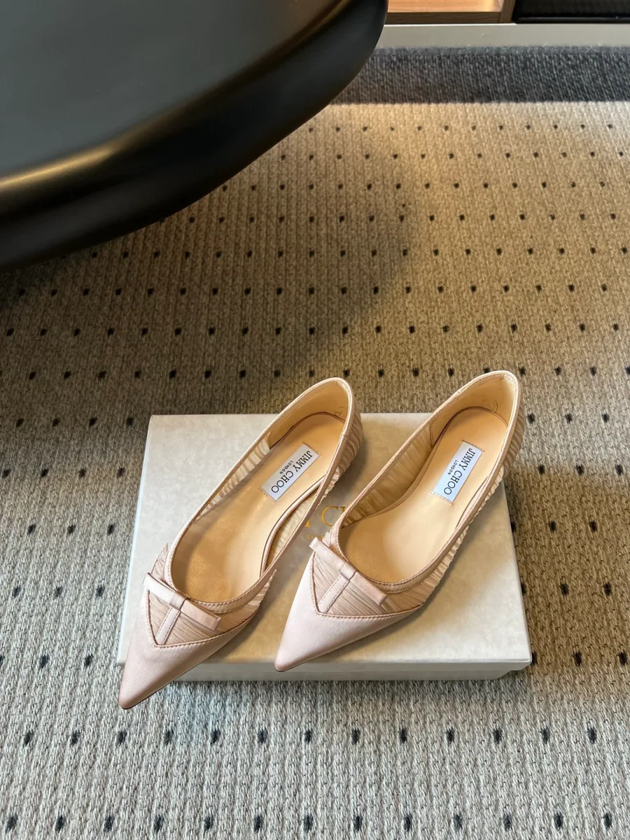 Пара бежевых балеток Jimmy Choo с плиссировкой, ракурс сбоку на фирменной коробке