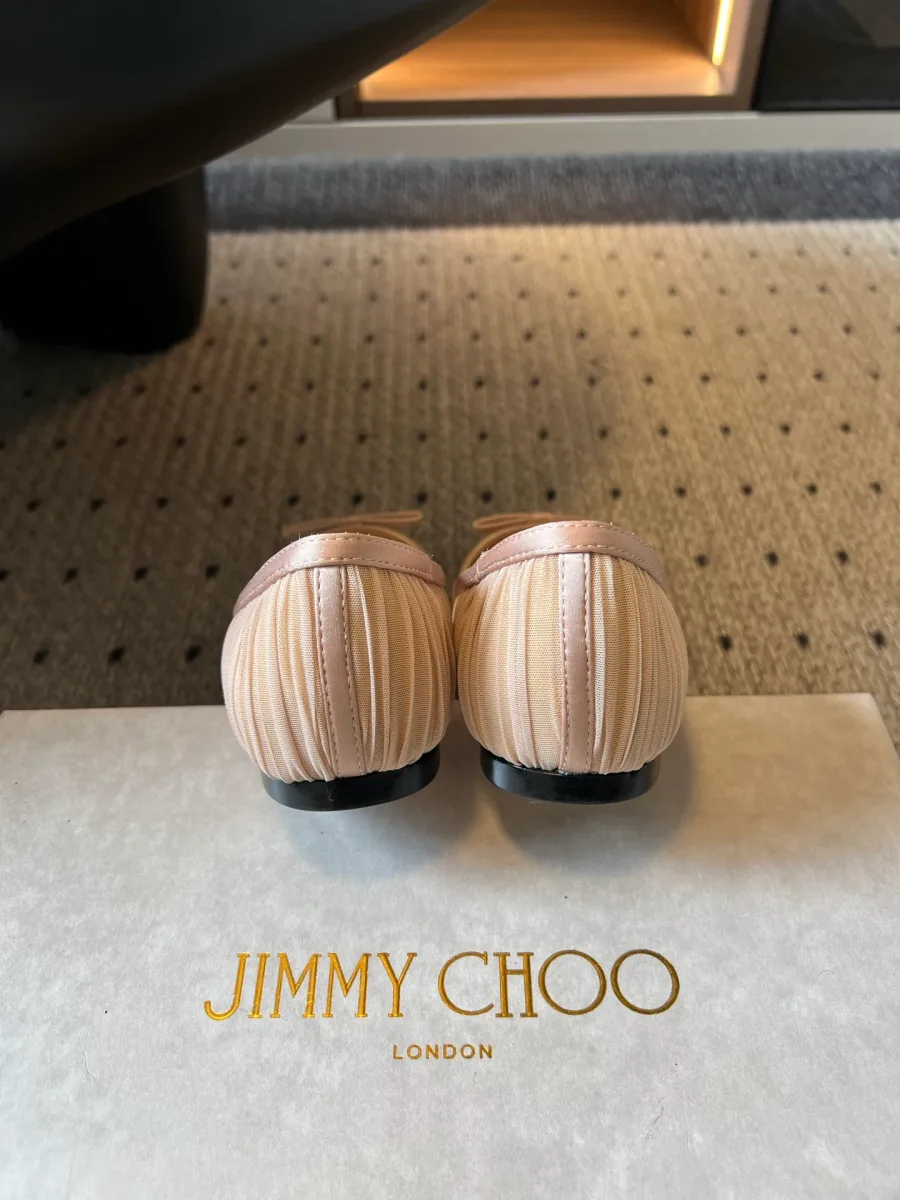 Вид на задники бежевых балеток с драпировкой на фоне коробки Jimmy Choo