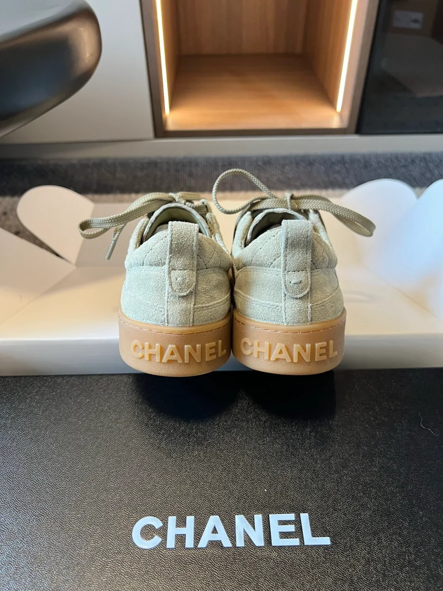 Задники светло-зелёных кедов с рельефной надписью Chanel на подошве крупным планом