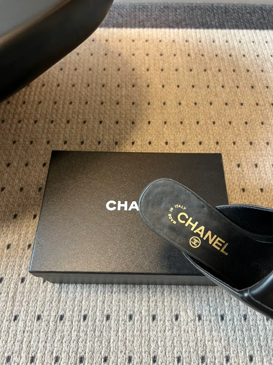 Крупный план кожаной стельки чёрной мюли с золотистой надписью Chanel