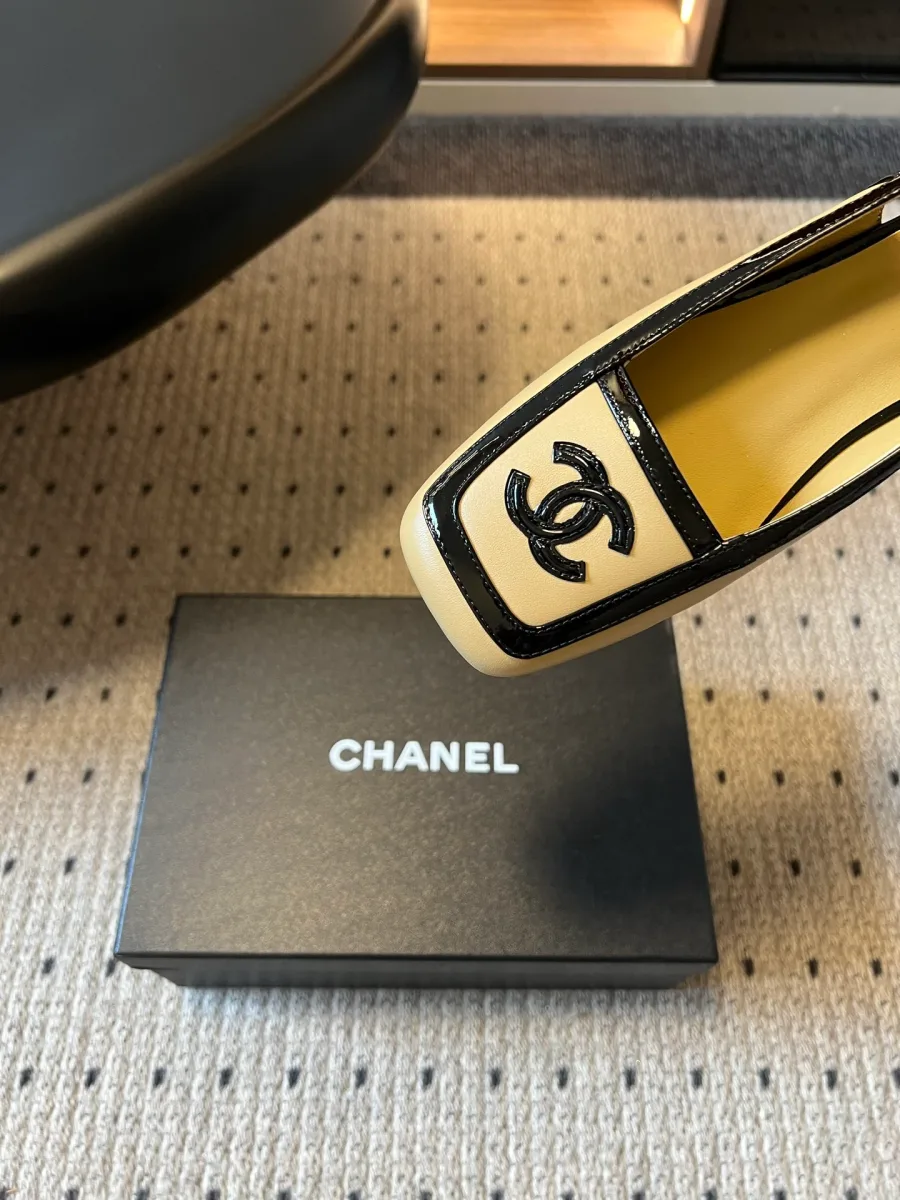 Крупный план мыска бежевого слингбэка Chanel с чёрным кантом и металлической монограммой CC