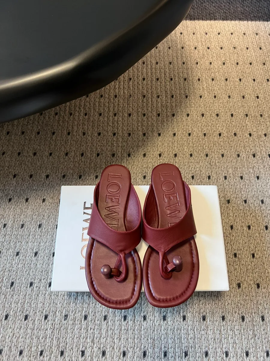 Бордовые кожаные шлепанцы через палец на коробке Loewe, вид сверху