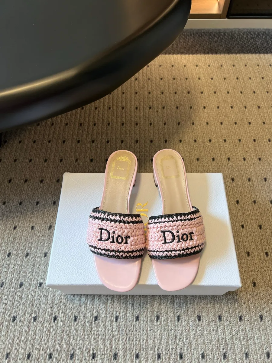 Пара розовых плетёных шлепанцев на низком каблуке с надписью Dior, вид сверху на коробке