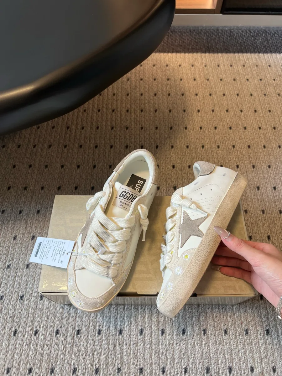 Боковой ракурс белых кед Golden Goose с замшевой звездой на фоне коробки