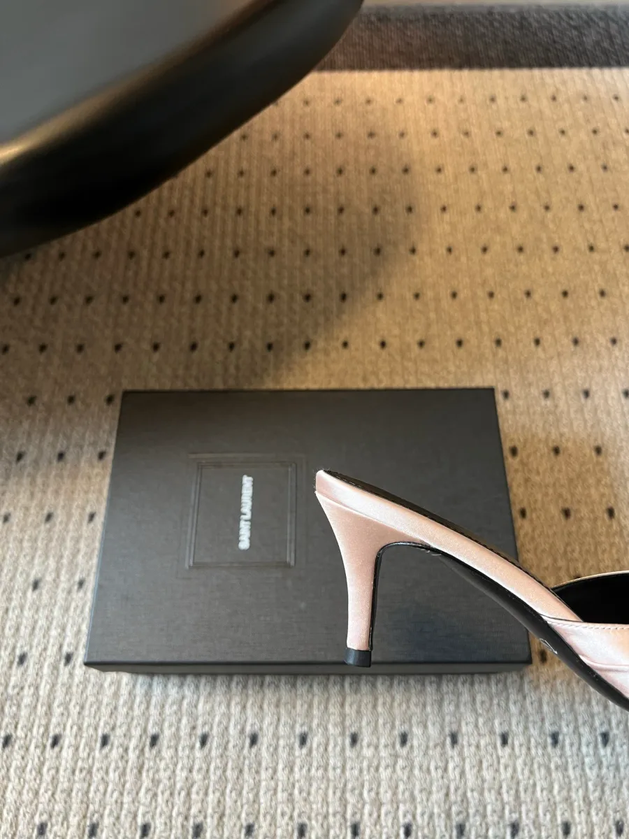 Каблук розовой мюли на фоне фирменной коробки Saint Laurent