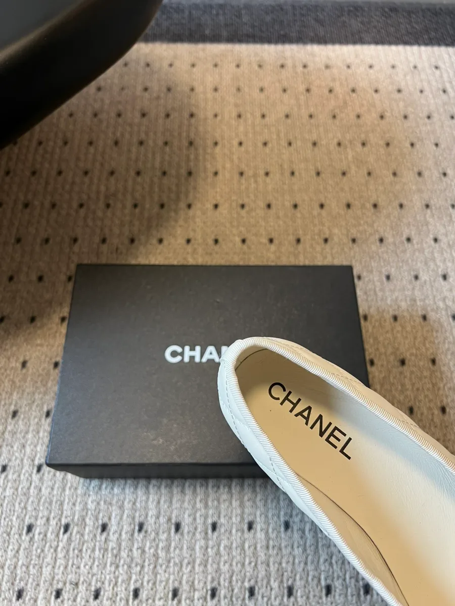 Крупный план кожаной стельки с тиснением Chanel внутри белой балетки