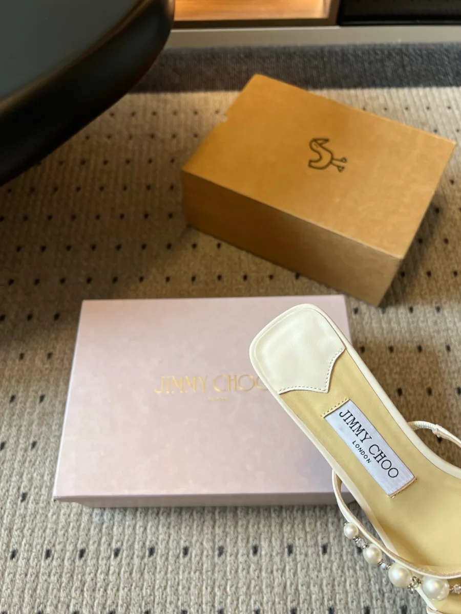 Крупный план стельки с золотистым логотипом Jimmy Choo London на светлой босоножке