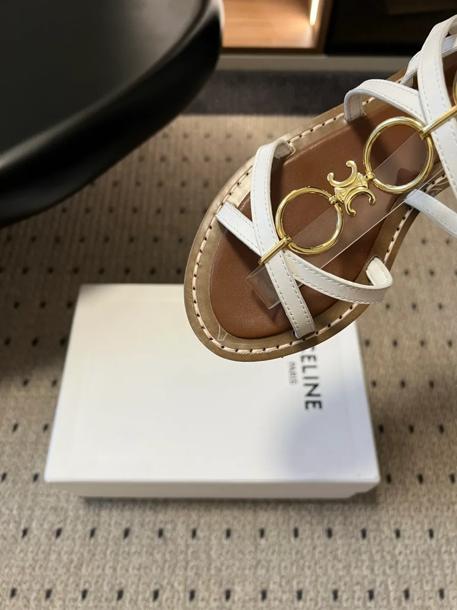 Крупный план золотистого металлического декора Triomphe на белых ремешках