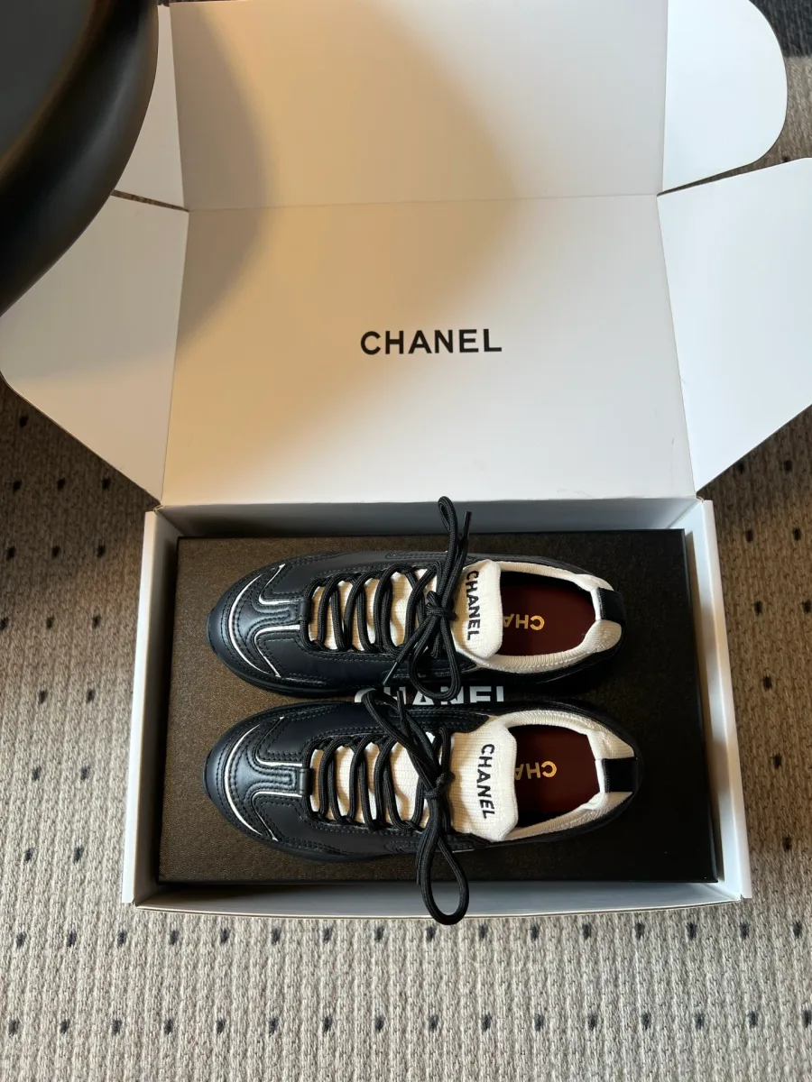 Пара кроссовок Chanel в коробке, вид сверху на шнуровку и стельки с логотипом