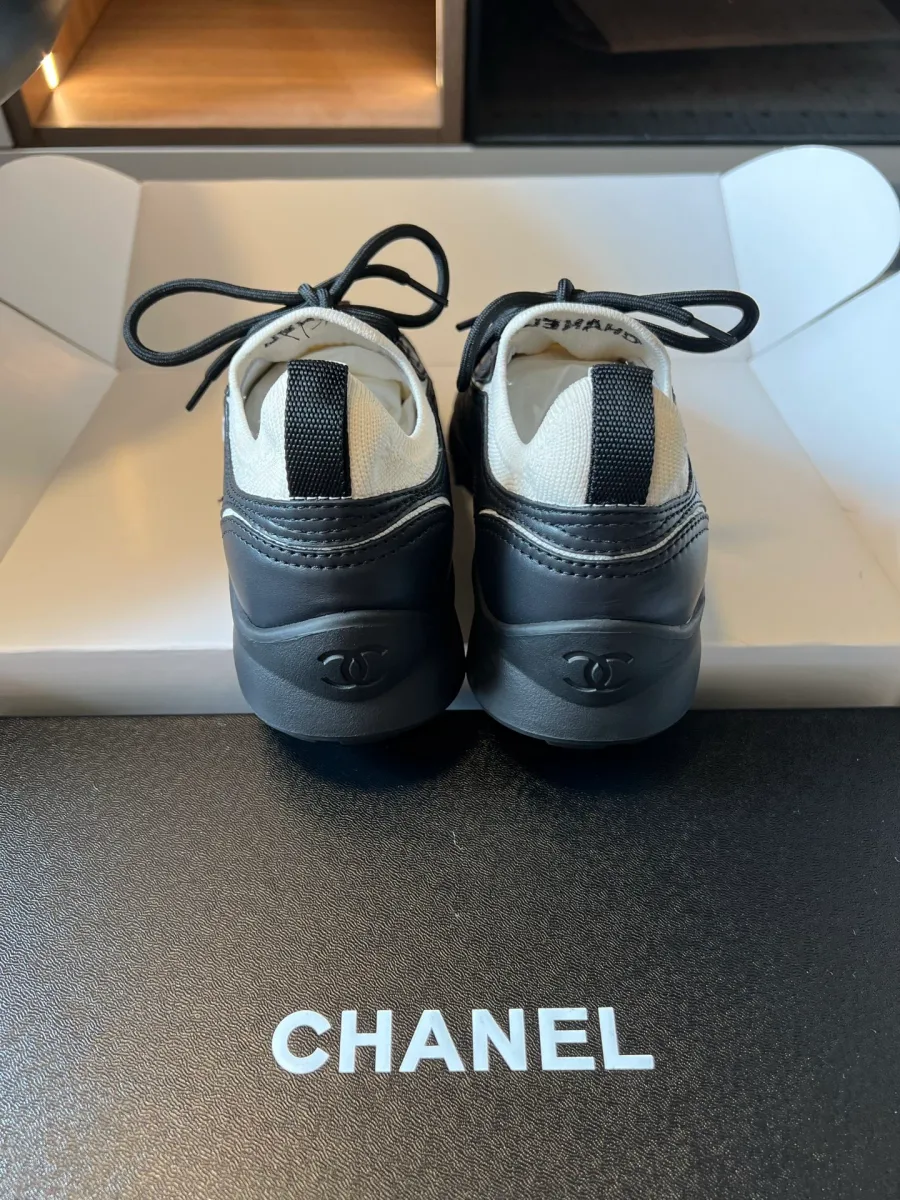 Задники чёрных кроссовок Chanel с белым кантом и тиснёным логотипом CC крупным планом