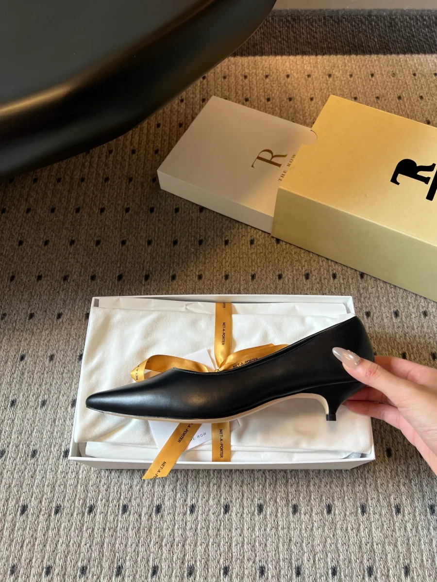 Профиль чёрной кожаной туфли с каблуком kitten heel в руке