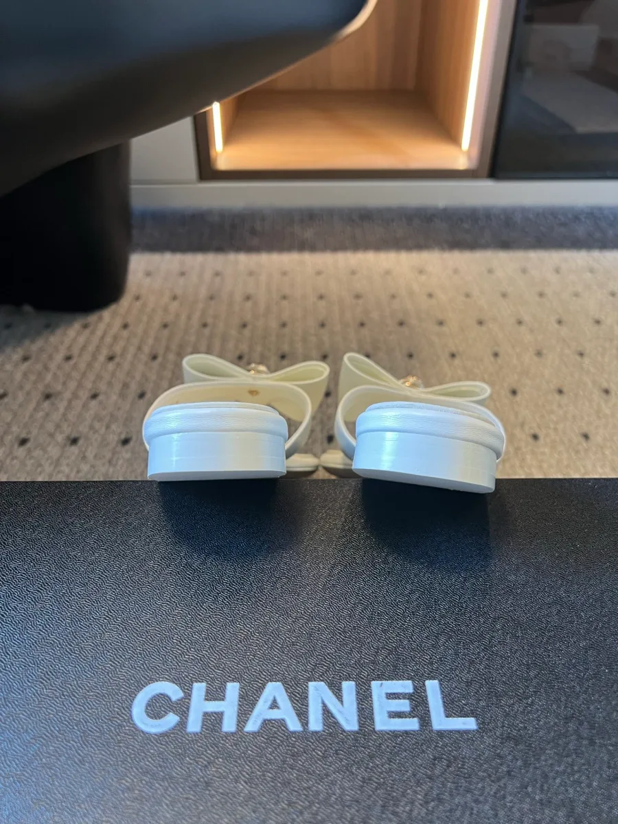 Вид на низкий каблук и заднюю часть белых шлепанцев Chanel