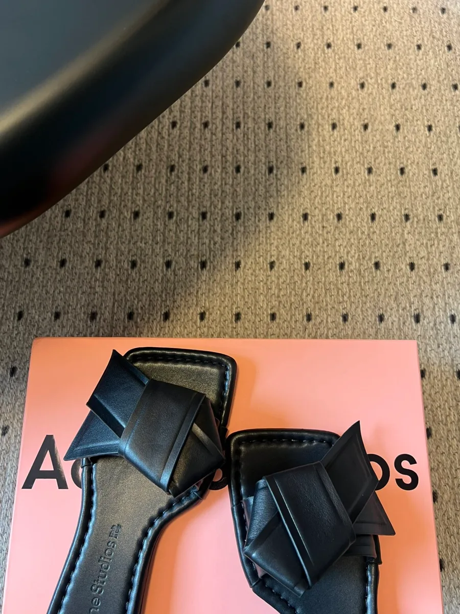 Детали носочной части чёрных шлёпанцев с акцентными складками кожи