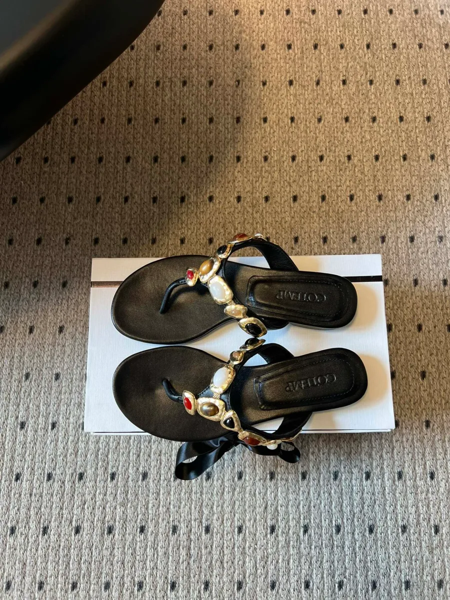 Вид сверху на пару чёрных кожаных шлёпанцев с декоративными вставками