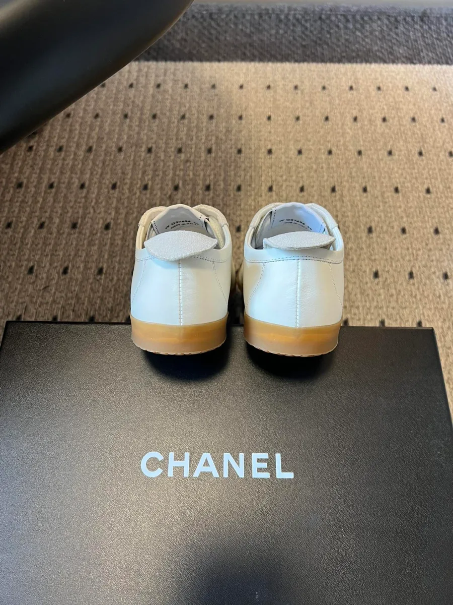 Задняя часть белых кед Chanel на чёрной коробке с логотипом