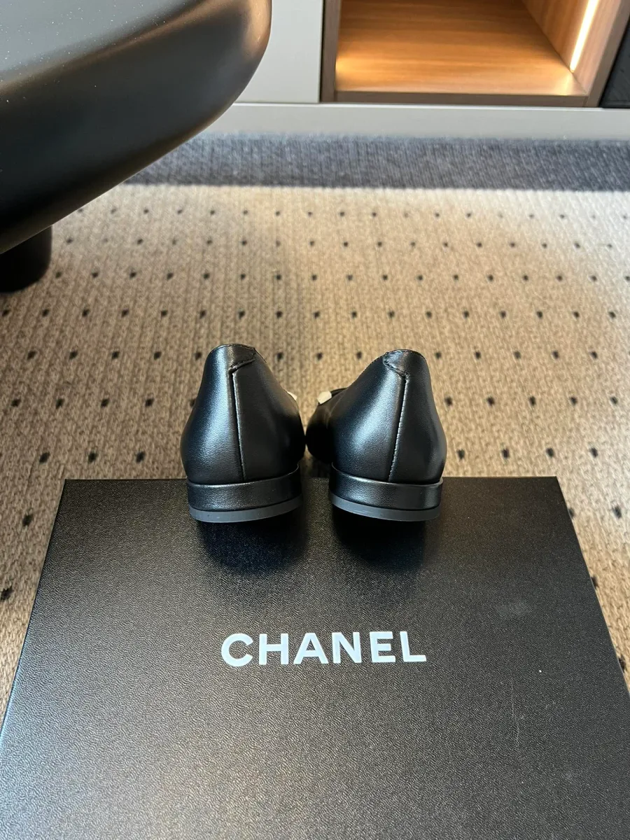 Задняя часть чёрных балеток Chanel на коробке бренда, вид со стороны пятки