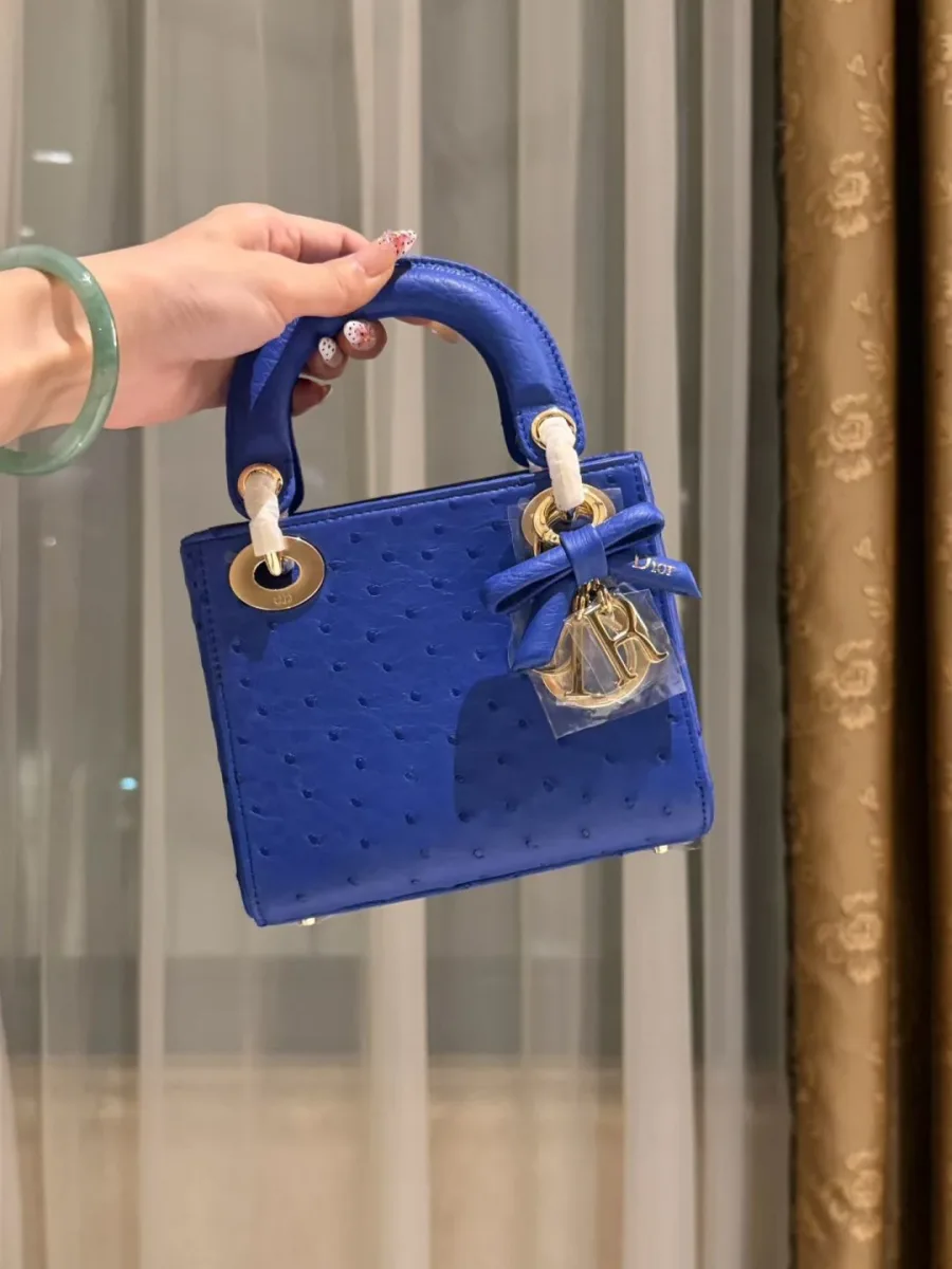 Синяя сумка Lady Dior из кожи страуса, вид спереди в руке