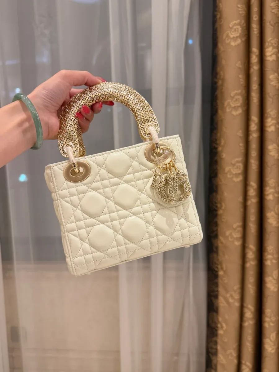 Молочно-белая сумка Lady Dior со стежкой Cannage и золотистыми ручками в руке