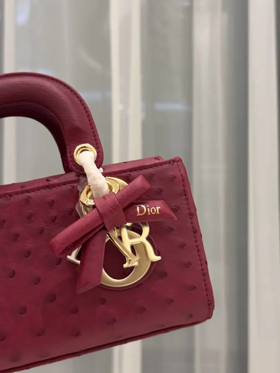 Крупный план золотистых шармов DIOR и кожаного банта на сумке Lady D-Joy