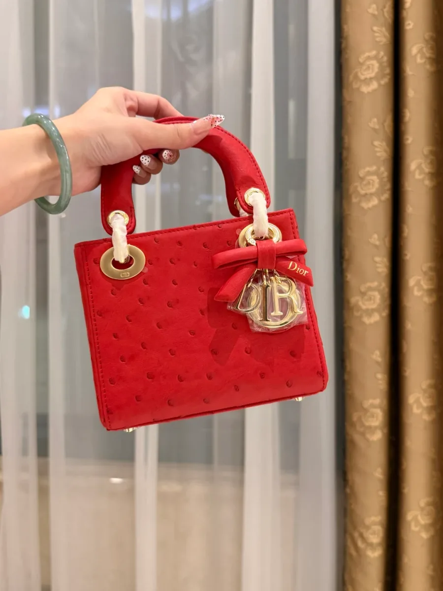 Красная сумка Lady Dior с фактурой кожи страуса и бантом на шарме, вид спереди