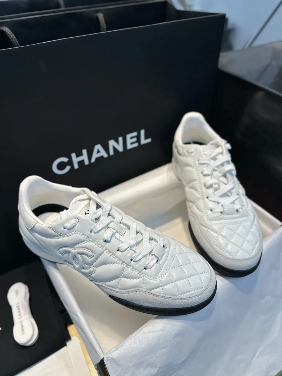 Белые кожаные кроссовки Chanel со стёганым узором в коробке, ракурс три четверти