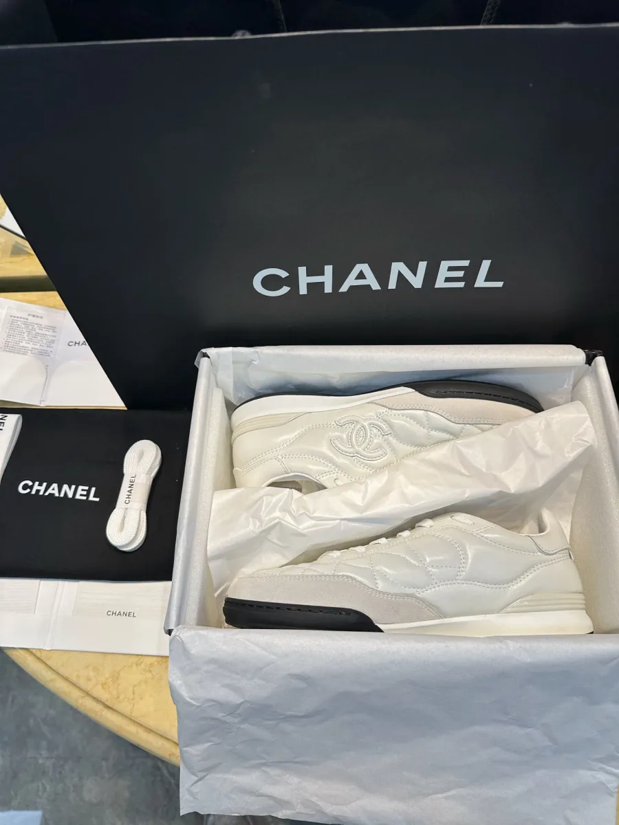Белые кроссовки Chanel в открытой фирменной коробке с упаковочной бумагой