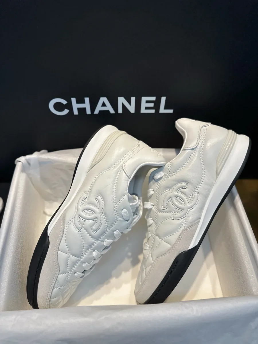 Пара белых кроссовок Chanel в коробке, вид на боковой профиль и подошву