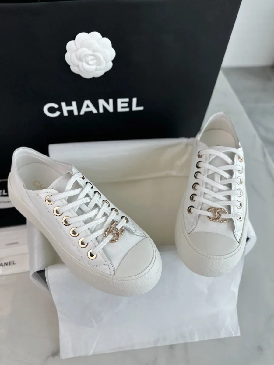 Белые кожаные кеды на платформе Chanel, вид спереди на фоне фирменной упаковки