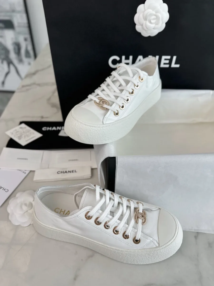 Белые кеды Chanel на белой коробке, вид сверху на шнуровку и язычок
