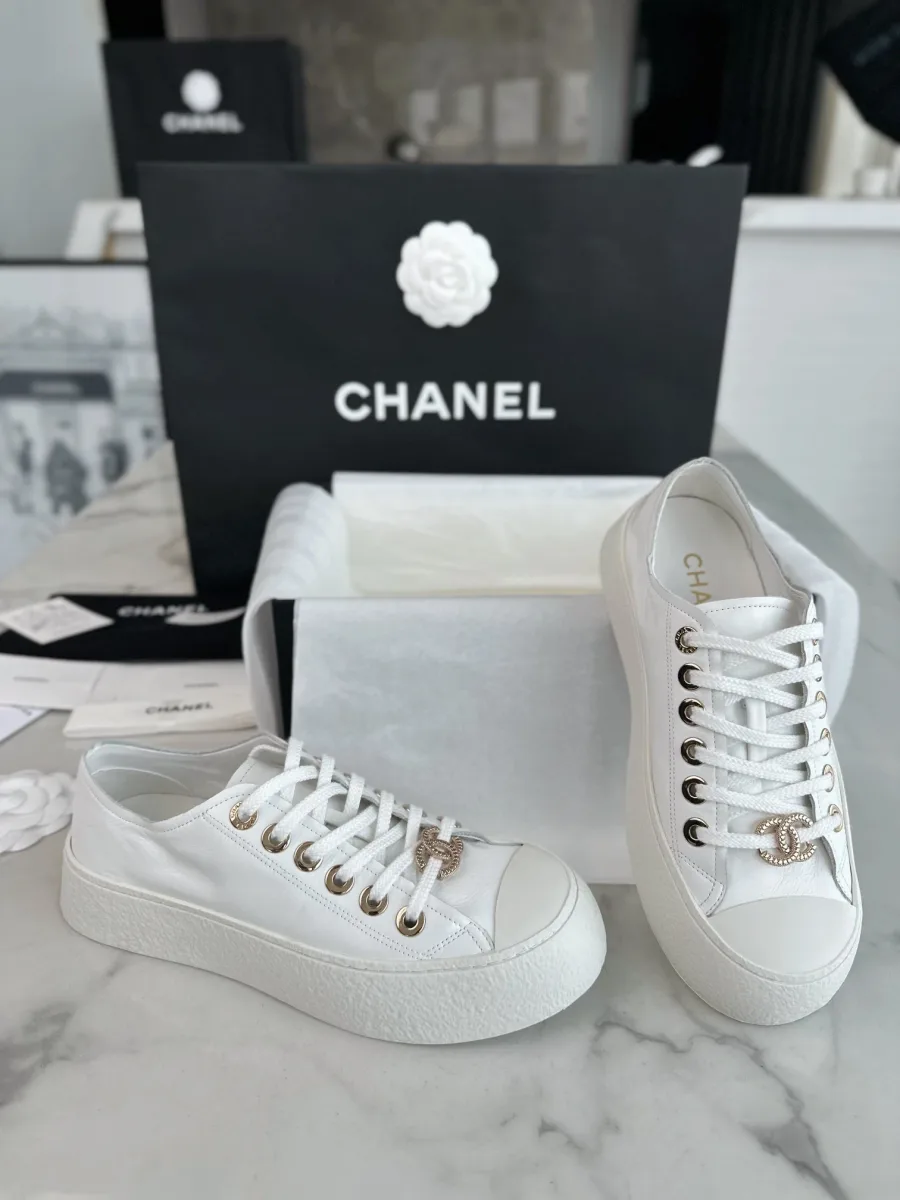 Пара белых кед Chanel, вид сбоку и спереди с золотистой фурнитурой