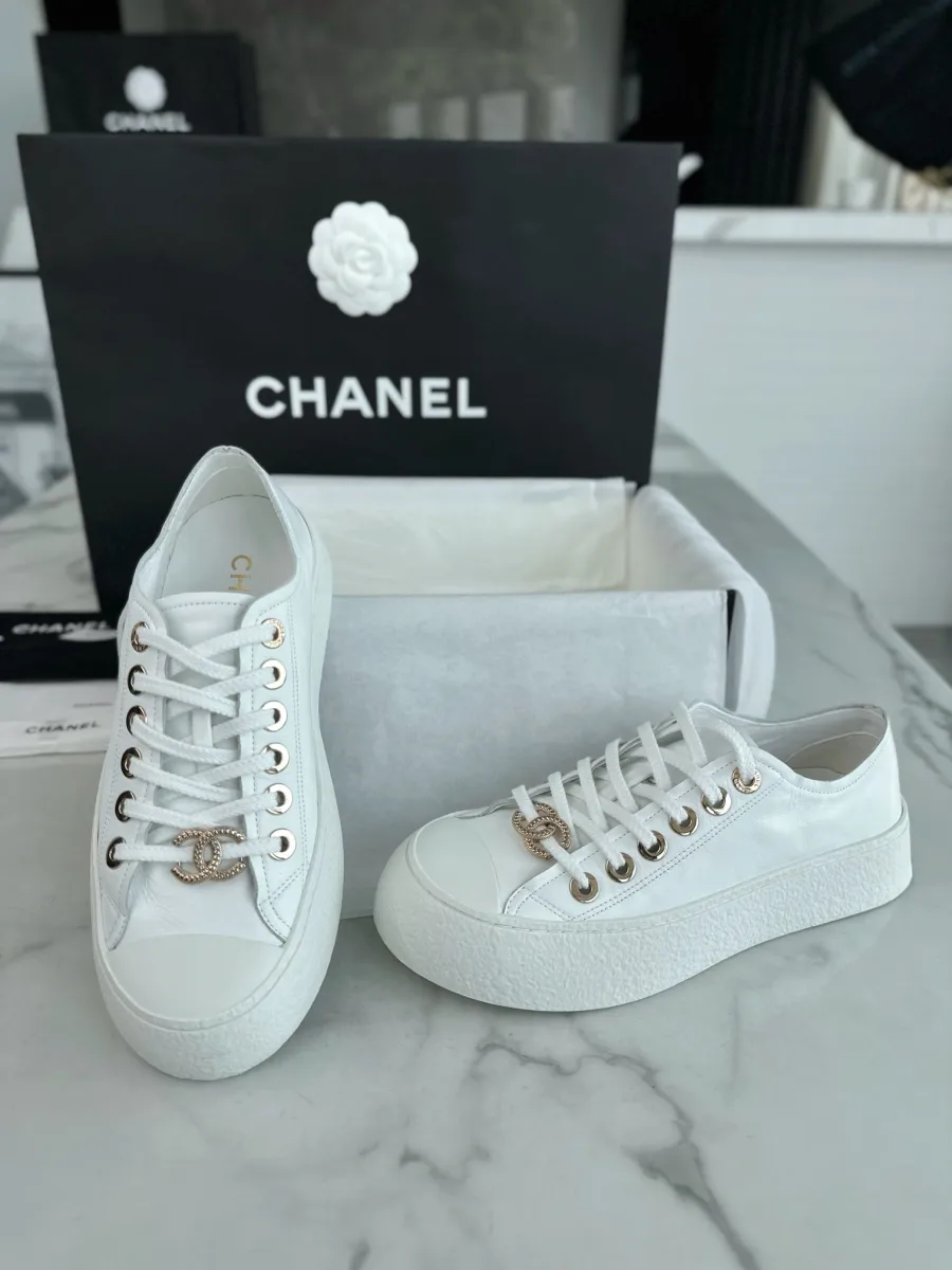 Белые кеды на платформе Chanel, ракурс спереди и сбоку на фоне упаковки