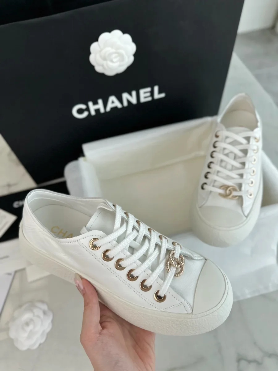 Белый кед Chanel в руке крупным планом, демонстрация мыска и шнуровки