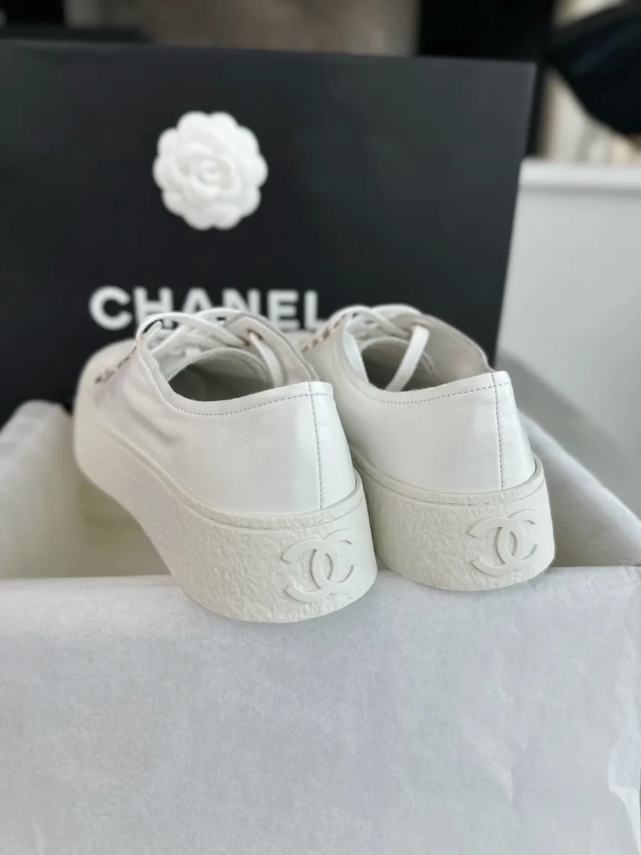 Задняя часть пары белых кед Chanel с крупной монограммой CC на подошве