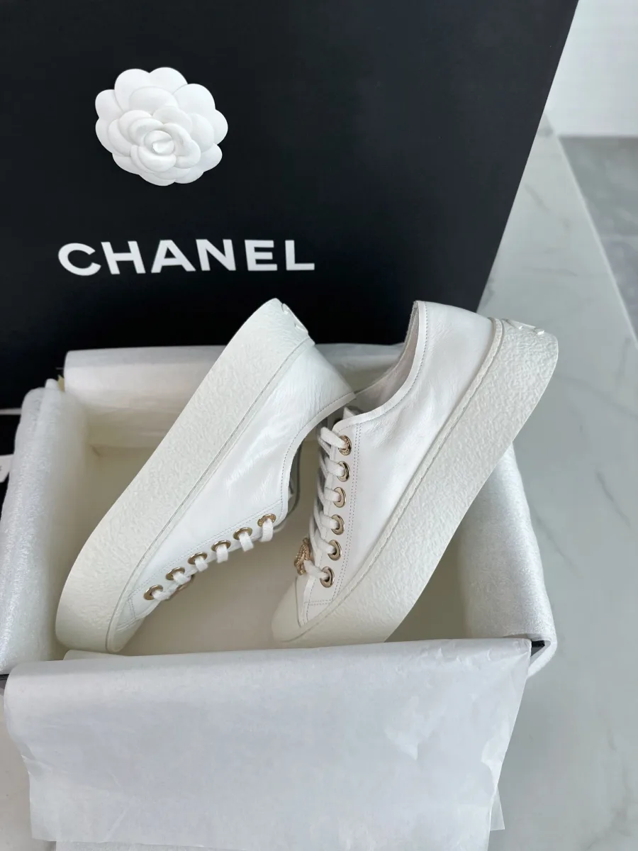 Пара белых кед Chanel внутри упаковочной коробки, вид на подошву и верх