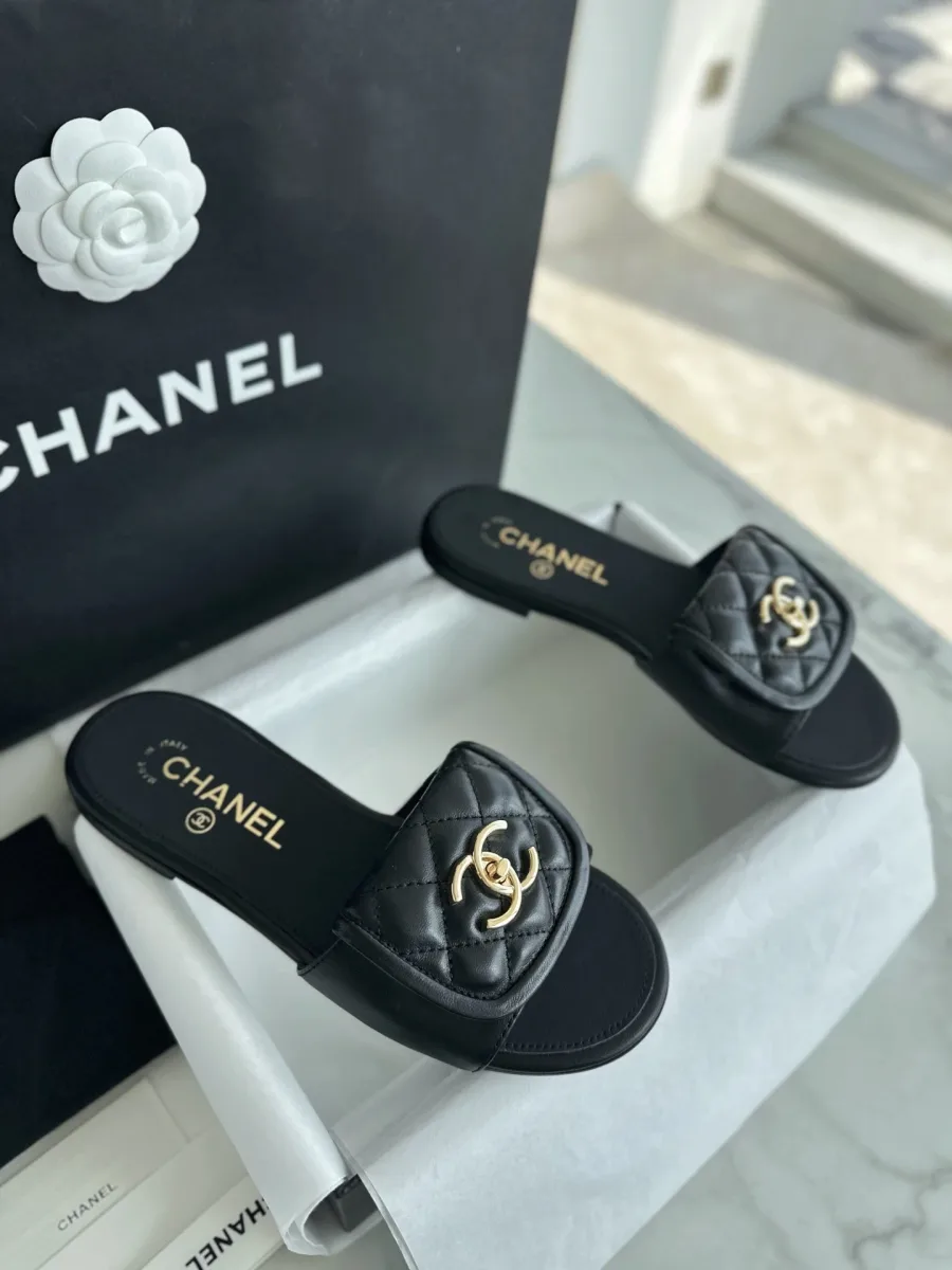 Пара чёрных шлёпанцев Chanel со стёганой союзкой в коробке, ракурс сбоку