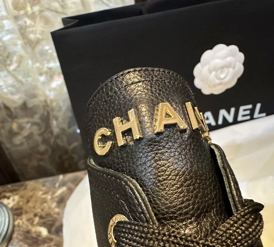 Золотистые объёмные буквы CHANEL на верхнем крае голенища