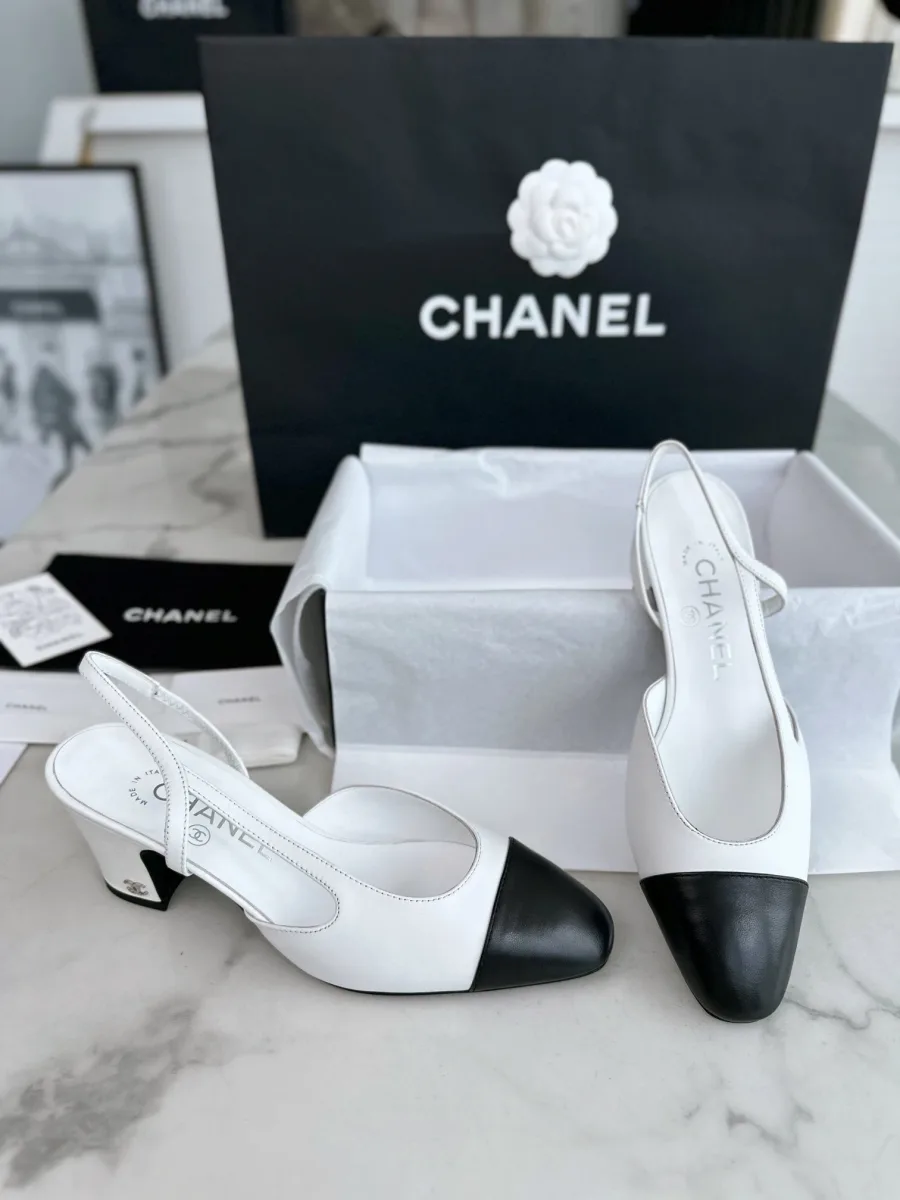 Бело-чёрные слингбэки Chanel на фоне фирменной коробки и пакета