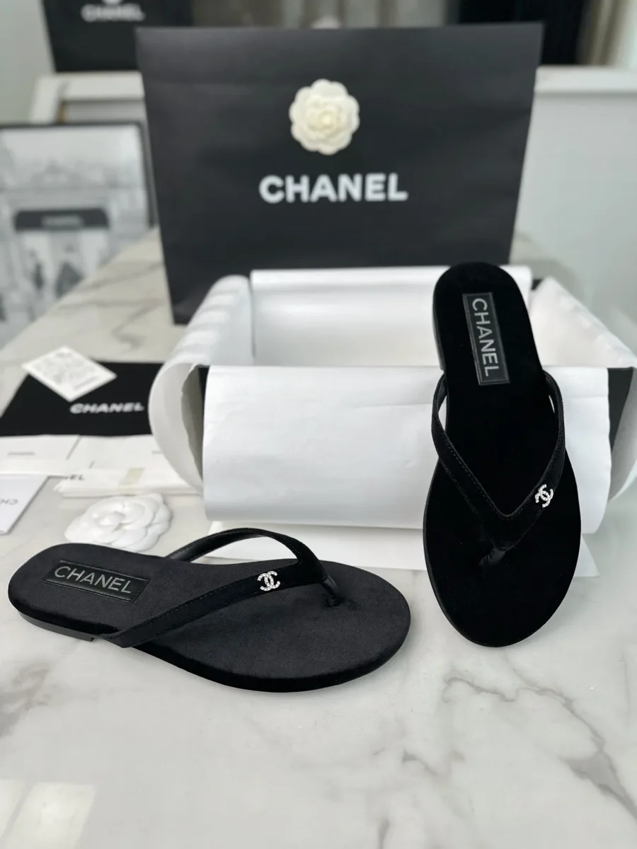 Пара чёрных бархатных шлепанцев рядом с фирменной коробкой Chanel
