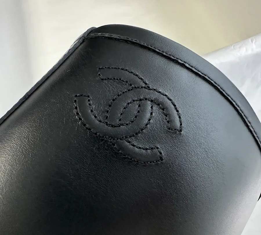 Вышитый логотип CC на верхнем крае голенища чёрного сапога Chanel крупным планом