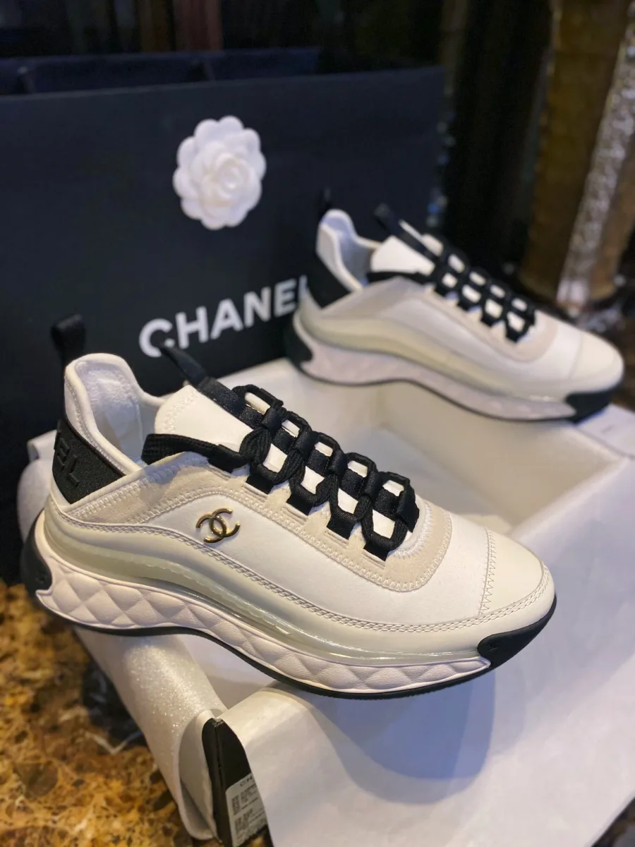Общий вид кроссовок Chanel сбоку на фоне фирменного пакета