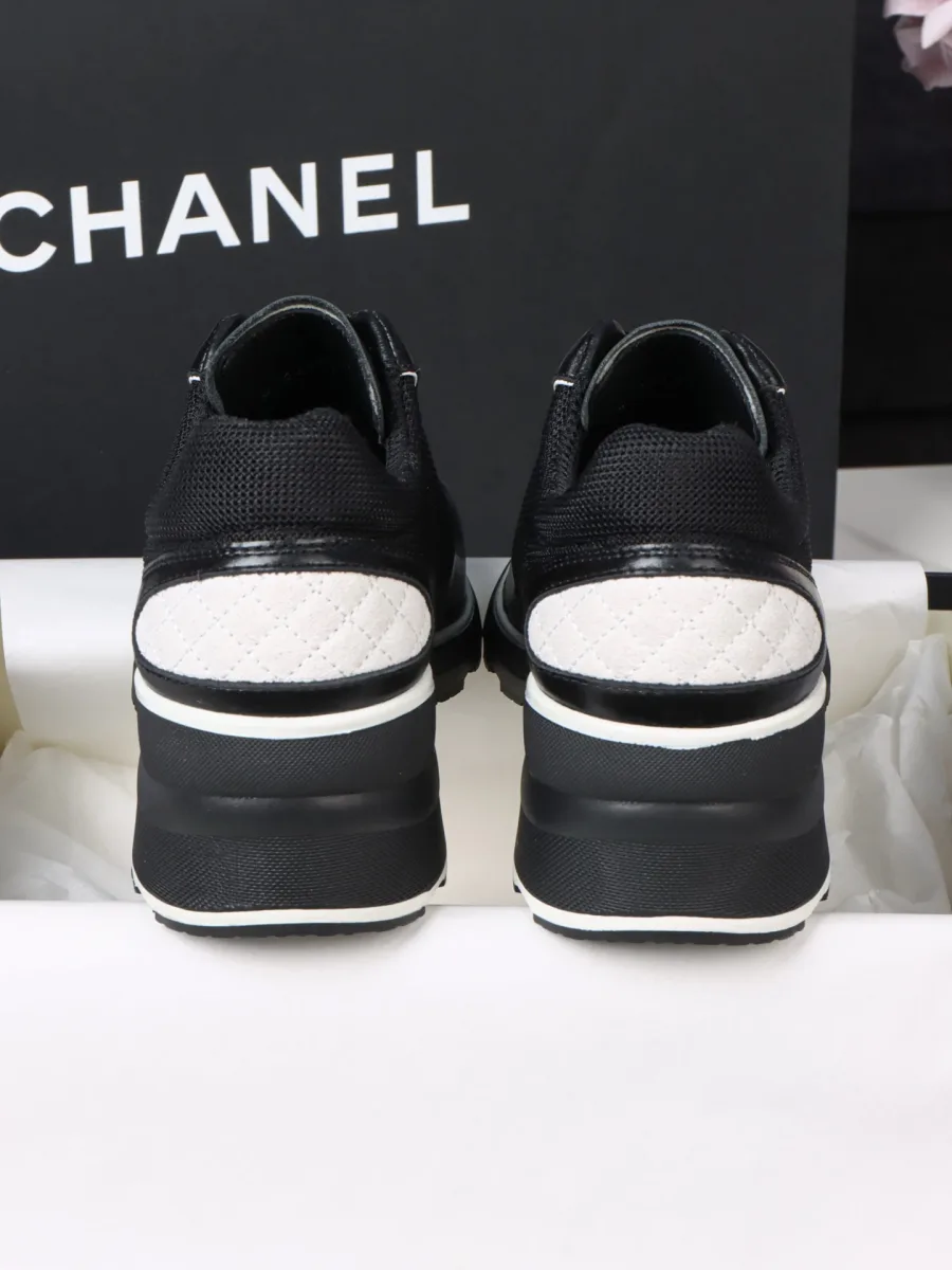 Вид сзади на пару чёрных кроссовок Chanel с белыми стегаными вставками на пятке