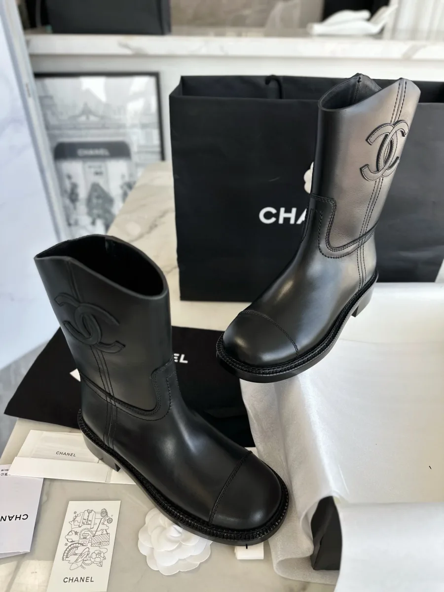 Чёрные кожаные сапоги Chanel на фоне фирменной упаковки, вид спереди