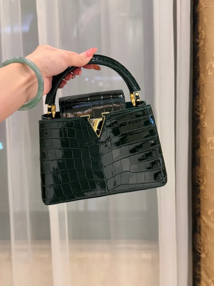 Тёмно-зелёная сумка Capucines BB из кожи крокодила с золотистой фурнитурой, вид спереди